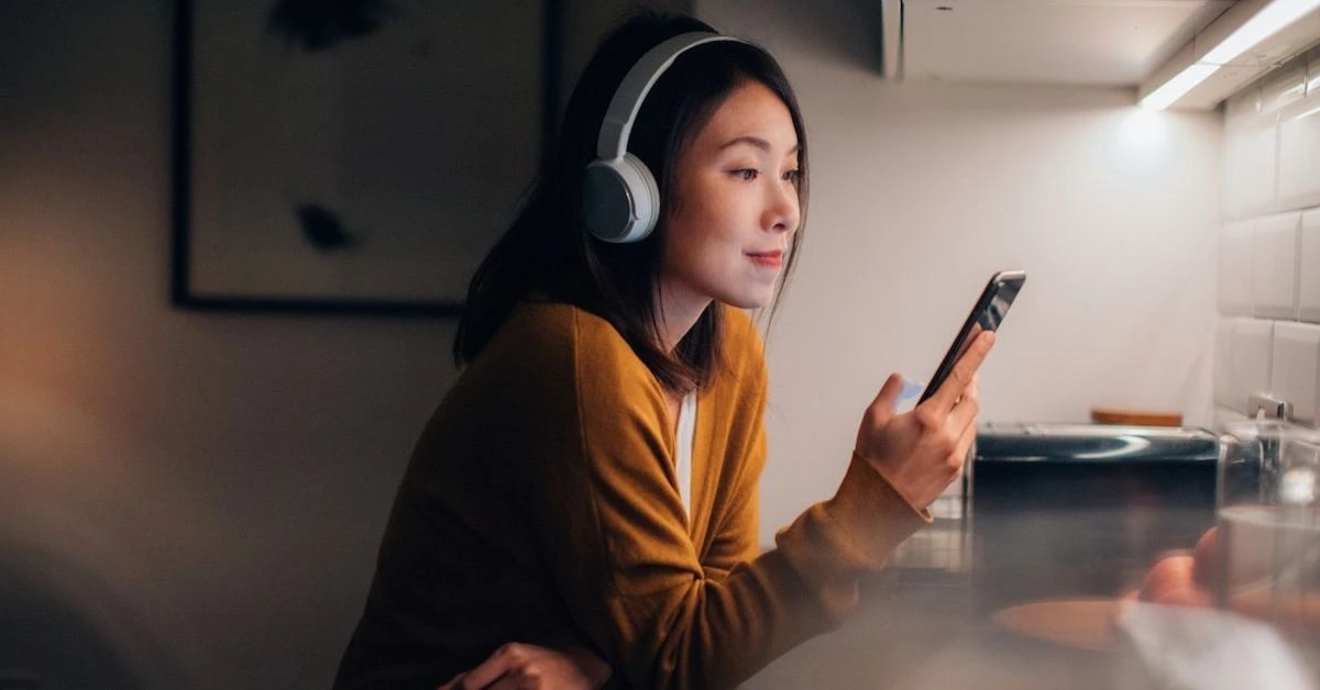 a woman wearing headphones and looking at a phone